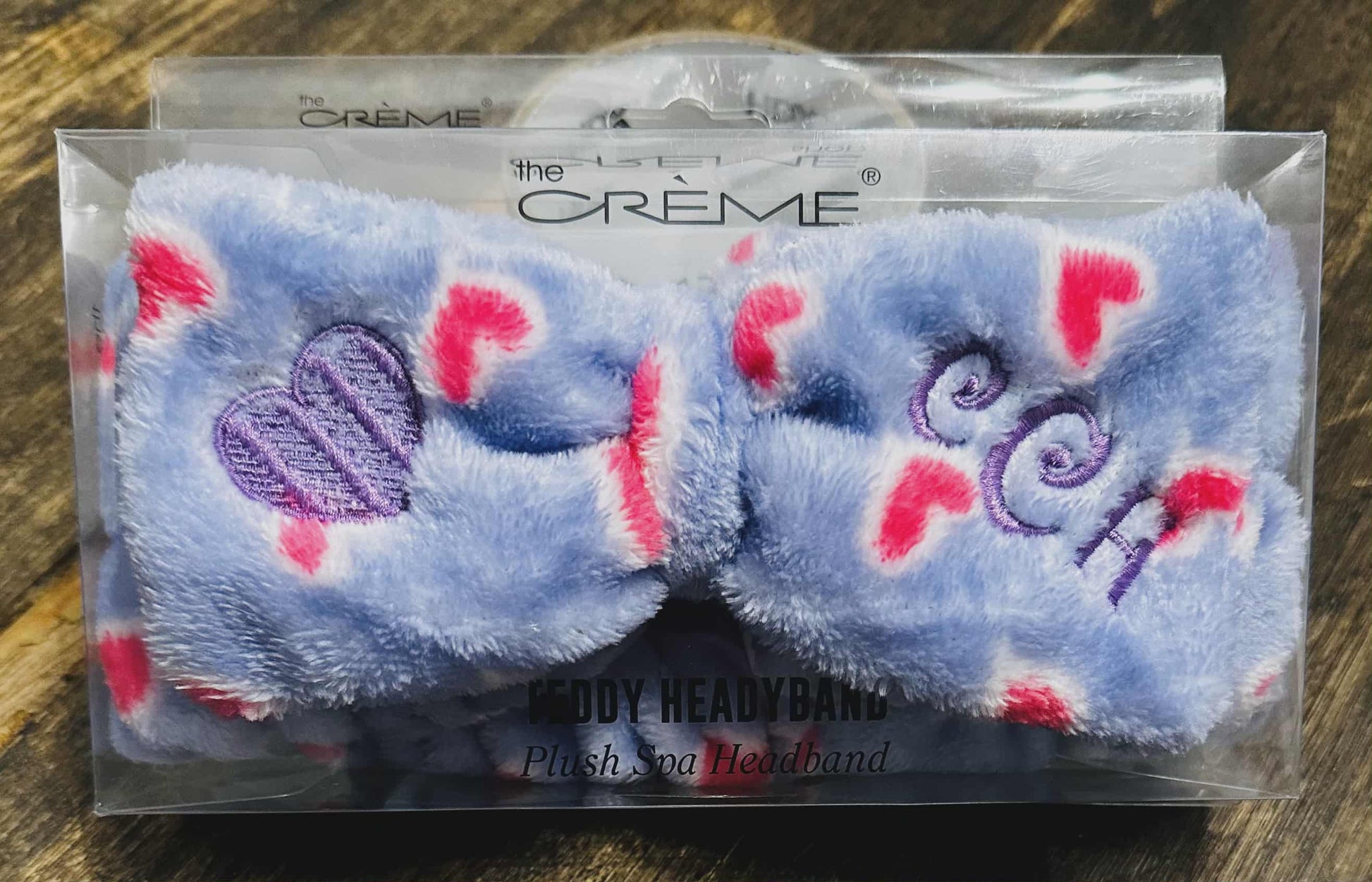 Plush headband with hearts and 'Creme' branding in clear packaging on a wooden surface.